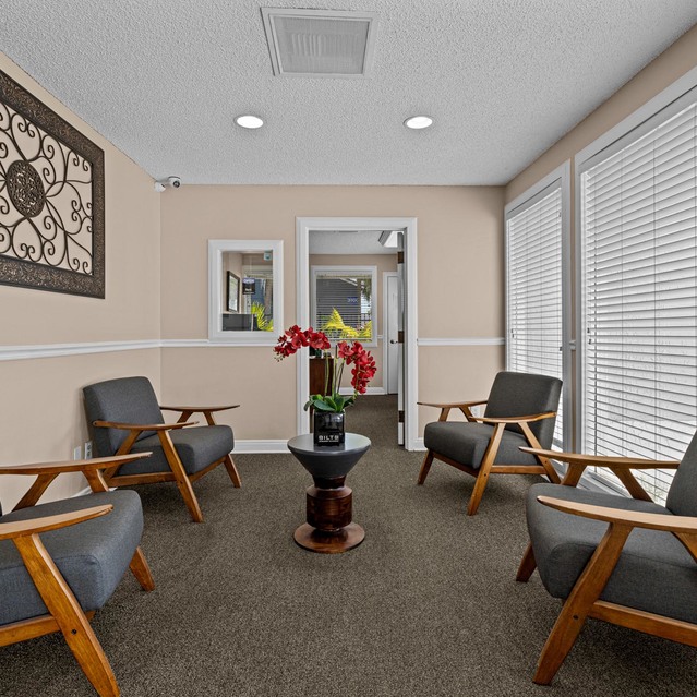 The Park at Veneto - Cozy Waiting Area with Four Wooden Chairs Around a Central Table Featuring a Potted Orchid